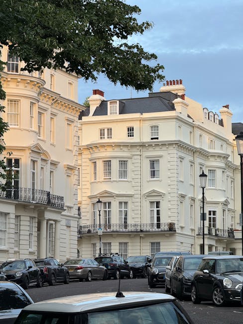 Photograph of a classic London townhouse with multiple floors featuring large sash windows and decorative white molding. The building's facade is composed of brick and painted plaster sections, with s